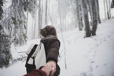 Rear view of man in snow covered forest