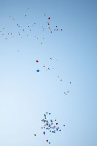 Low angle view of balloons flying against blue sky