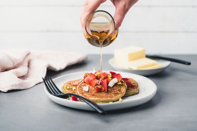 Cropped hand of person pouring honey on meal in plate