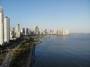 Sea by city buildings against clear sky