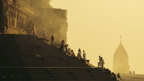 People on staircase by building against sky