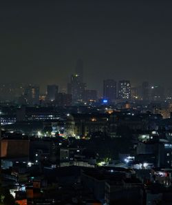 Illuminated city buildings against clear sky at night