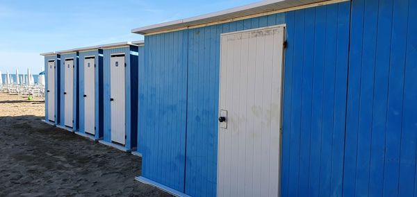 Wooden posts on beach by building against blue sky