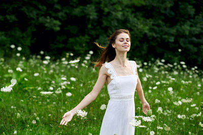 Portrait of young woman standing against plants