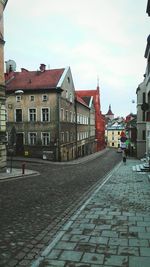 Road amidst buildings in town against sky