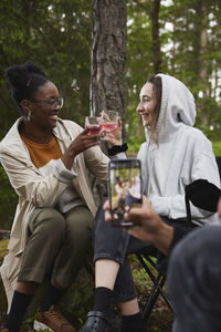 Friends having toast at camping in forest