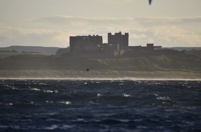 Buildings by sea against sky during sunset