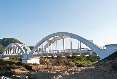 White railway bridge over river against sky