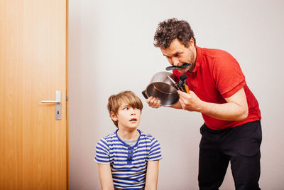 Father and son standing against wall