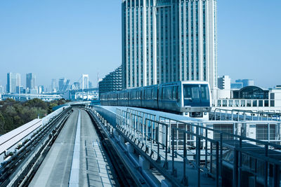 Subway train on railway bridge against buildings in city