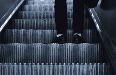 Low section of man standing on escalator