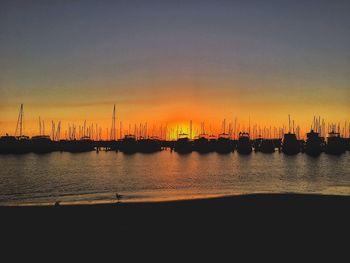 Sailboats moored on sea against sky during sunset