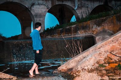 Full length of man standing on arch bridge