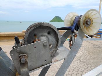 Close-up of rusty wheel by sea against sky