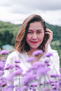 Portrait of smiling woman by purple flowers outdoors