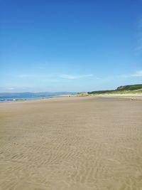 Scenic view of beach against blue sky