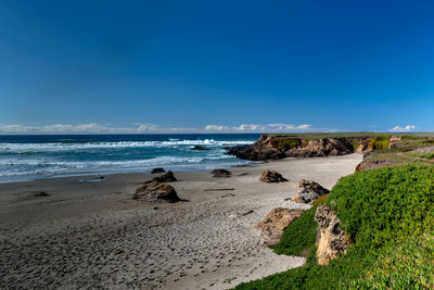 Scenic view of beach against blue sky