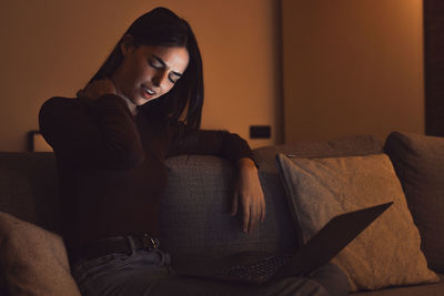 Young woman sitting on sofa at home
