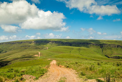 Scenic view of road amidst field against sky