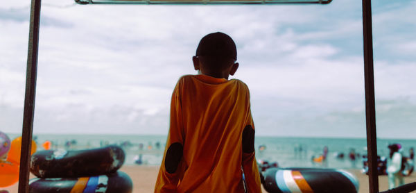 Rear view of man standing in sea against sky