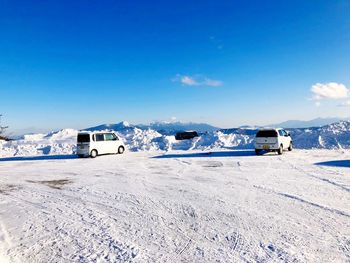 Houses on snowcapped mountain against blue sky