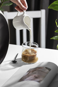 Cropped hand pouring coffee on table