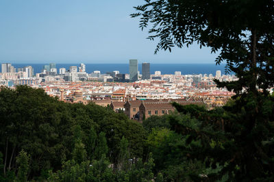 Trees and buildings in city against clear sky