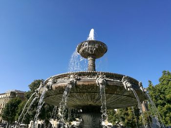 Low angle view of fountain against clear blue sky