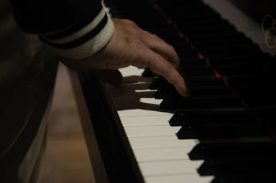 Cropped hand playing piano in darkroom