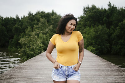 Portrait of smiling young woman against trees