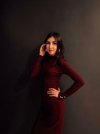 Portrait of smiling young woman standing against gray background