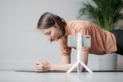 Side view of woman using mobile phone while sitting on table