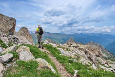 Rear view of man hiking on mountain against sky