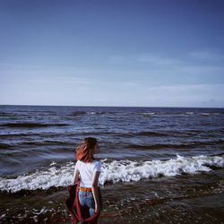 Rear view of woman at beach against sky