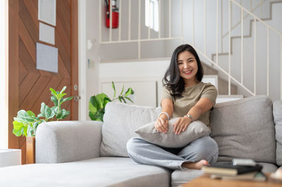 Young woman using mobile phone while sitting on sofa at home