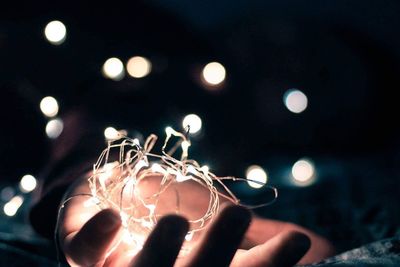 Cropped hand holding illuminated lights in darkroom