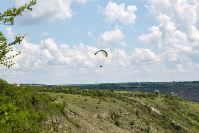 Ukraine flag paraglider flying midday over canyon in butuceni, moldova