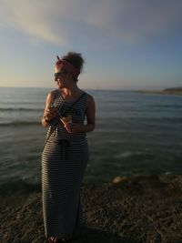 Full length of woman standing at beach against sky
