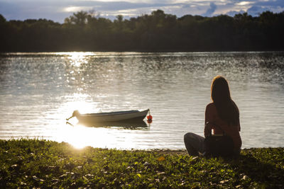 Side view of people sitting on boat in lake