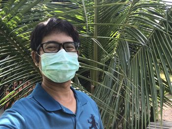 Portrait of young man standing against plants