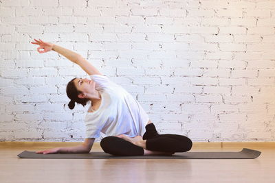 Woman with arms raised against wall