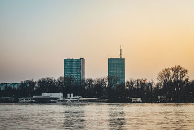 River by buildings against clear sky during sunset