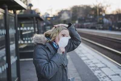 Woman wearing protective mask on train station platform