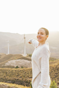 Side view of smiling young woman standing on land