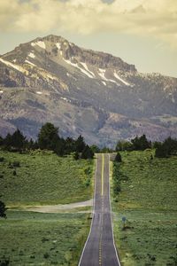 Road leading towards mountains against sky