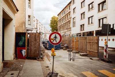 Road sign on street by buildings in city