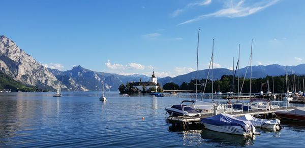 Sailboats moored in harbor against sky