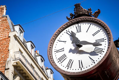 Low angle view of clock on building against clear sky