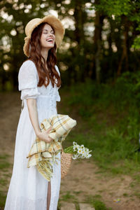 Young woman standing against trees