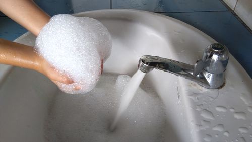 Close-up of hands being washed under faucet at home